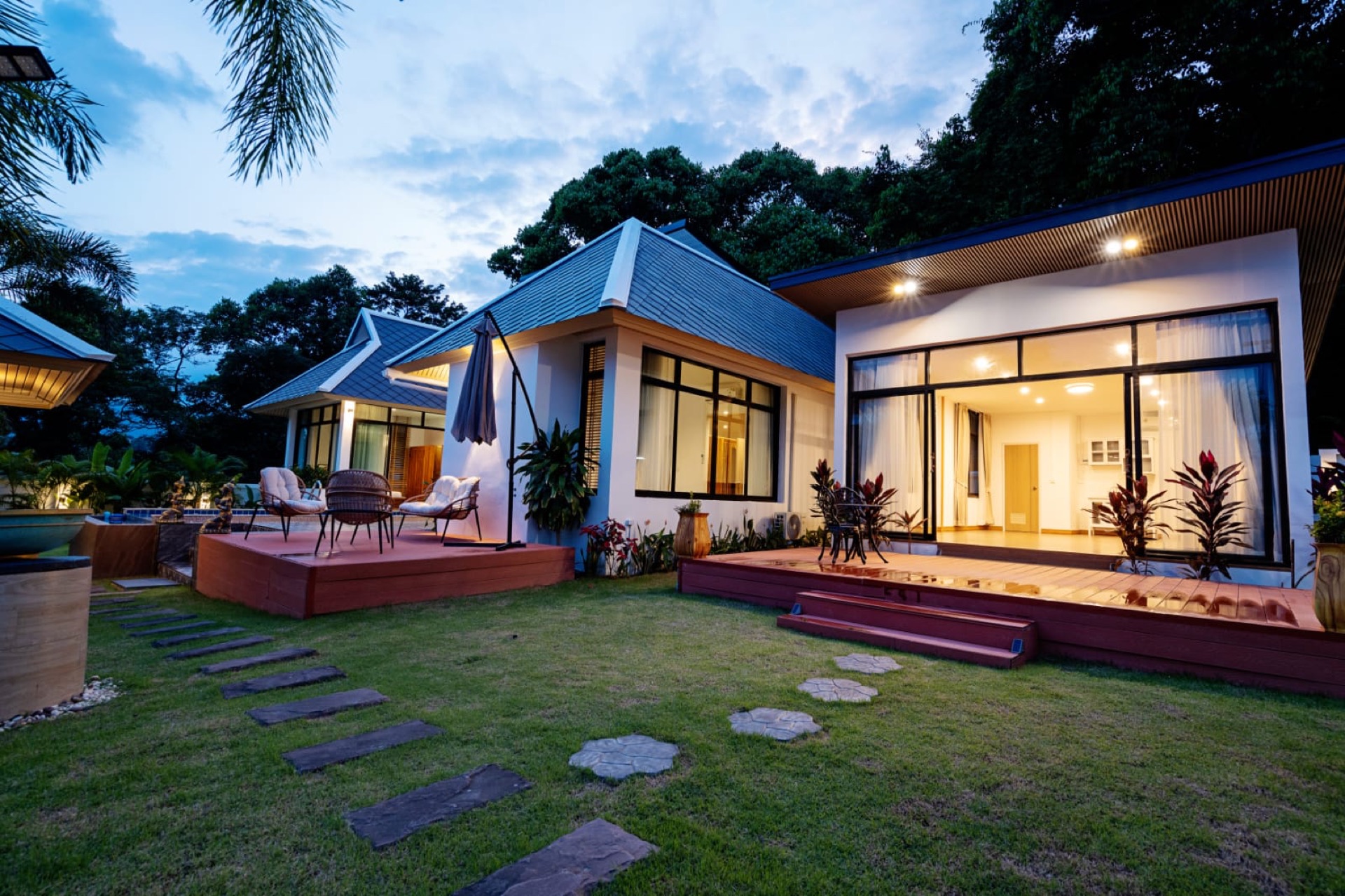 Villa contemporaine éclairée au crépuscule, jardin paysager et terrasses, à Koh Samui