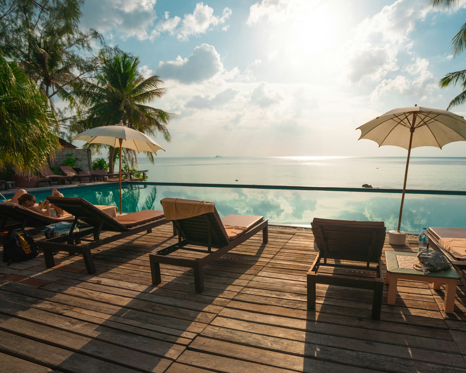 Piscine de villa entourée de palmiers, transats en bois